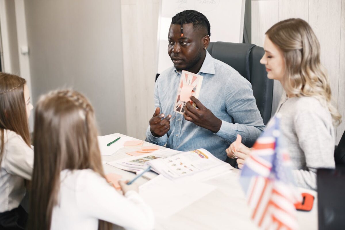 Teacher guiding diverse students in an English language lesson with a British flag card.